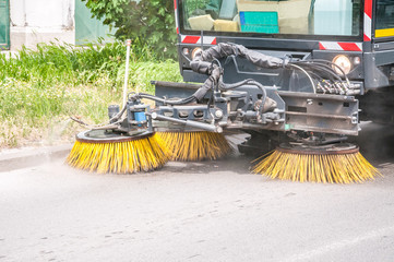 Street sweeper vehicle washing walkway and road with water and cleaning with vacuum rotating brushes, with motion blur