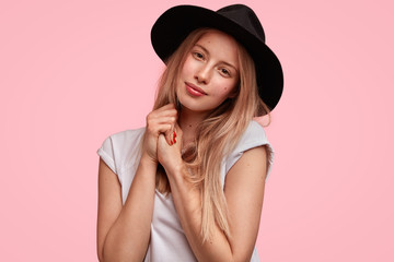 People, beauty, style and facial expressions concept. Adorable young European woman looks with pleased expression as being delighted after date with boyfriend, isolated over pink background.