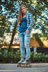 Obraz premium Portrait of a beautiful girl with long hair wearing fleece shirt and jeans in rollers, standing in the park in summer day.