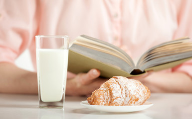 Enjoying relaxing moment with a book, croissant and glass of milk