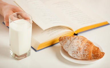 Enjoying relaxing moment with a book, croissant and glass of milk