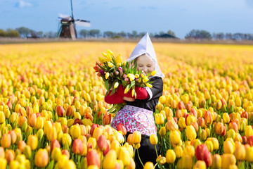 Child in tulip flower field. Windmill in Holland. - obrazy, fototapety, plakaty
