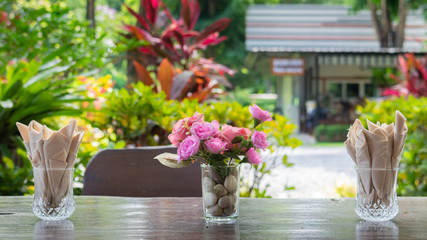 Tissue in glass and colorful flower under wooden table in a resort.