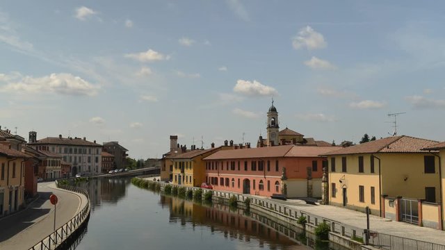 Cityscape of Gaggiano, just outside of Milan, Italy. Colourful houses reflected in the Naviglio Grande canal waterway.