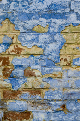 Blue stained wall with damaged paint. Yellow bricks are seen under it