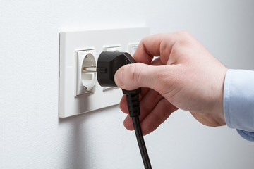 Male hand puts plug in the socket