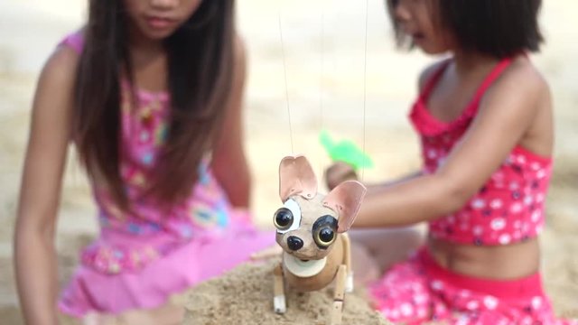Sister and sister are playing at the beach with the chihuahua puppet
