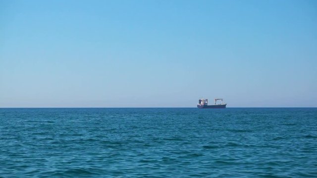 Calm sea with clear blue sky and cargo ship on the horizon