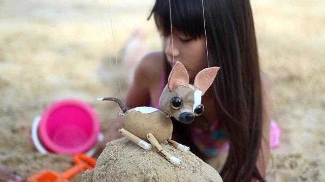 Little girl playing sand at the beach, happy with her puppy dog.
