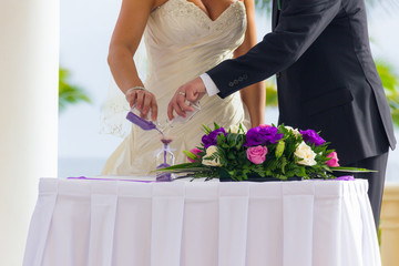 Wedding couple practice blending of sands ceremony with flowers bouquet on table