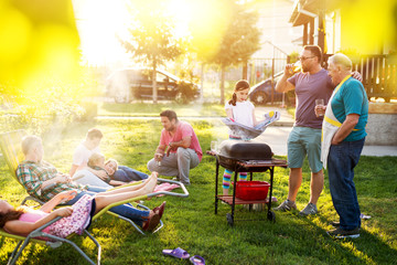 Familly gathered and is having a picnic toasting talking and grilling in their backyard on a...