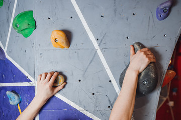 Close-up of artificial hooks and hands of climber on climbing wall
