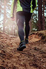 Athlete climbs up the hill along the forest trail. An active way of life.