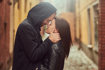 Bearded man and brunette girl kissing, on the background of the old European street.