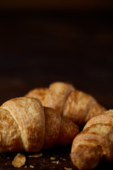 Tasty buttery croissants on an old wooden table, close-up, selective focus, shallow depth of field.