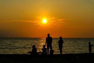 silhouette people play with two dog on beach sunset