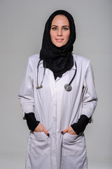 Arab female doctor posing and smiling isolated on a grey background.