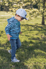 Child blonde 3-4 years in blue with hat and sunglasses running around the park