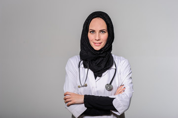 Arab female doctor posing and smiling isolated on a grey background.