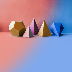 Abstract geometric figures. Three-dimensional dodecahedron pyramid tetrahedron cube rectangular objects on blue pink background. Bright platonic solids still life background. Blank space