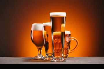 close up view of arrangement of glasses of beer on orange backdrop