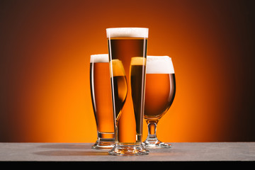 close up view of arrangement of glasses of beer on orange backdrop