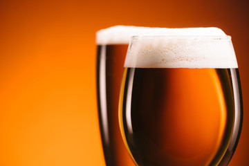 close up view of arrangement of glasses of beer on orange backdrop