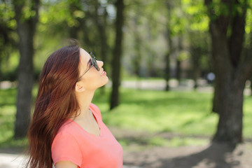 smiling young beautiful girl looking up, pretty woman in sunglasses and pink t-shirt, open air 