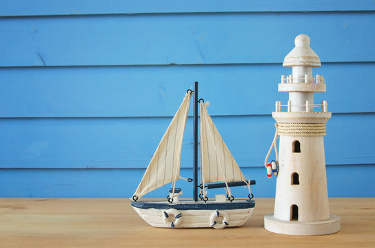 vacation and summer image with lighthouse and boat over blue wooden planks background.