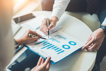 Two business point a pen to each other above chart report at meeting or negotiation in the office.