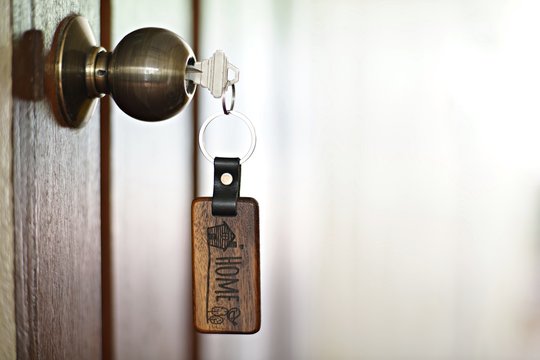 House key with home keyring in keyhole, property concept