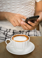 Woman using mobile phone and drink coffee.