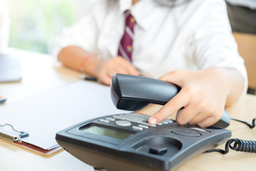 Fototapeta premium Woman finger pressing number button on telephone to make a call at office.