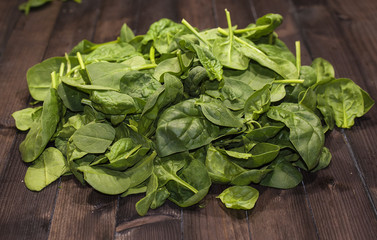 A mountain of Basil leaves on a wooden table.