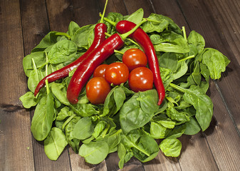 Tomatoes and spicy Mexican pepper on Basil leaves on wooden table.