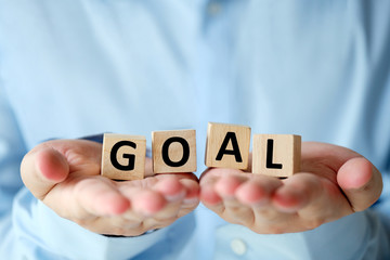 Goal, business word on wooden cubes in man hands, success in business concept