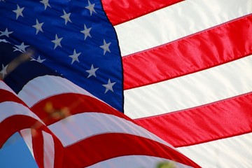 Obraz premium Close Up on American Flag Stars and Stripes Waving against Blue Sky Backlit by Afternoon Sun