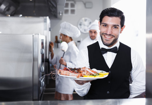 Waiter with seafood dish in kitchen of restaurant