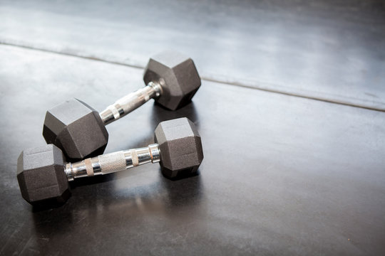 two Metal dumbbells on the black floor in gym . sport fitness equipment with copy space