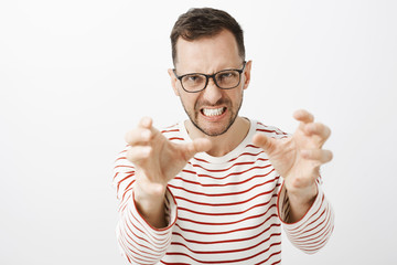 Indoor shot of angry pissed off european guy in black glasses, pulling hands towards camera and...