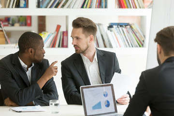 Young african american worker expressing thoughts on financial issue of new startup company project at business briefing. Caucasian manager listening to opponent opinion on development strategies