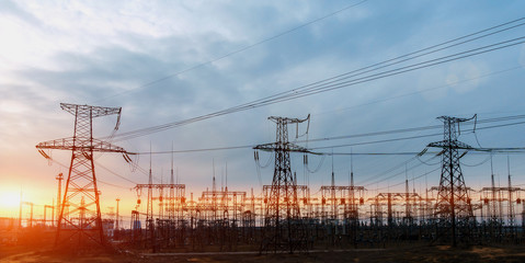 distribution electric substation with power lines and transformers, at sunset