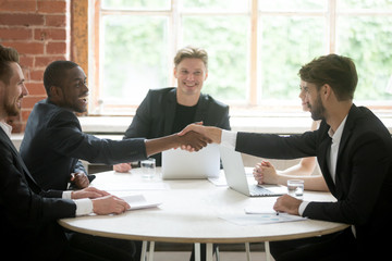 Smiling african american welcoming on board business partner by handshake at corporate meeting. Company team cheerfully greeting new colleague. Partnership, coworking, cooperation, negotiation concept