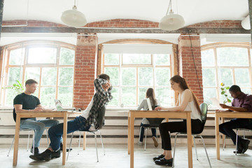 Multiethnic group of freelance workers working in modern coworking space. Students studying at university open space room getting ready for exams. Concept of diversity and multiracial education