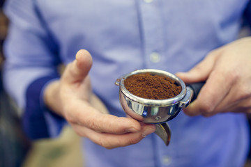 Photo of barista man with ground coffee in hands