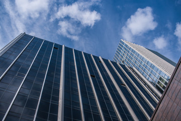 Obraz na płótnie Canvas Bottom view of facades of modern glass office buildings and blue sky up it.