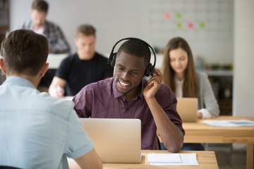 African american worker consulting client using wireless headset in modern coworking office. Black...