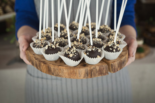 Cakepops on wooden platter in waitress hands