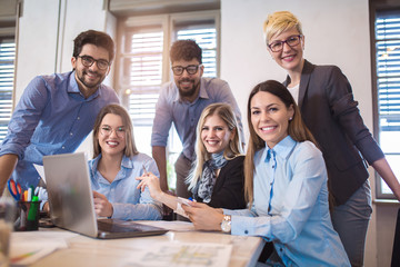  Group of young business people in smart casual wear working together in creative office using laptop.