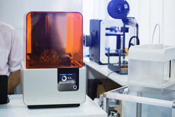 A stereolithography 3d printer in the laboratory prints a structure from a photopolymer. On the display the process indicator and the number of layers. Creating scaled model by UV polymerization.